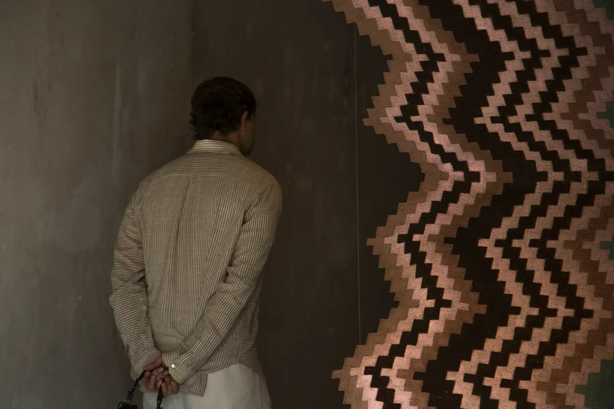 Visitor before a woven textile installation, Aki Aora 2025