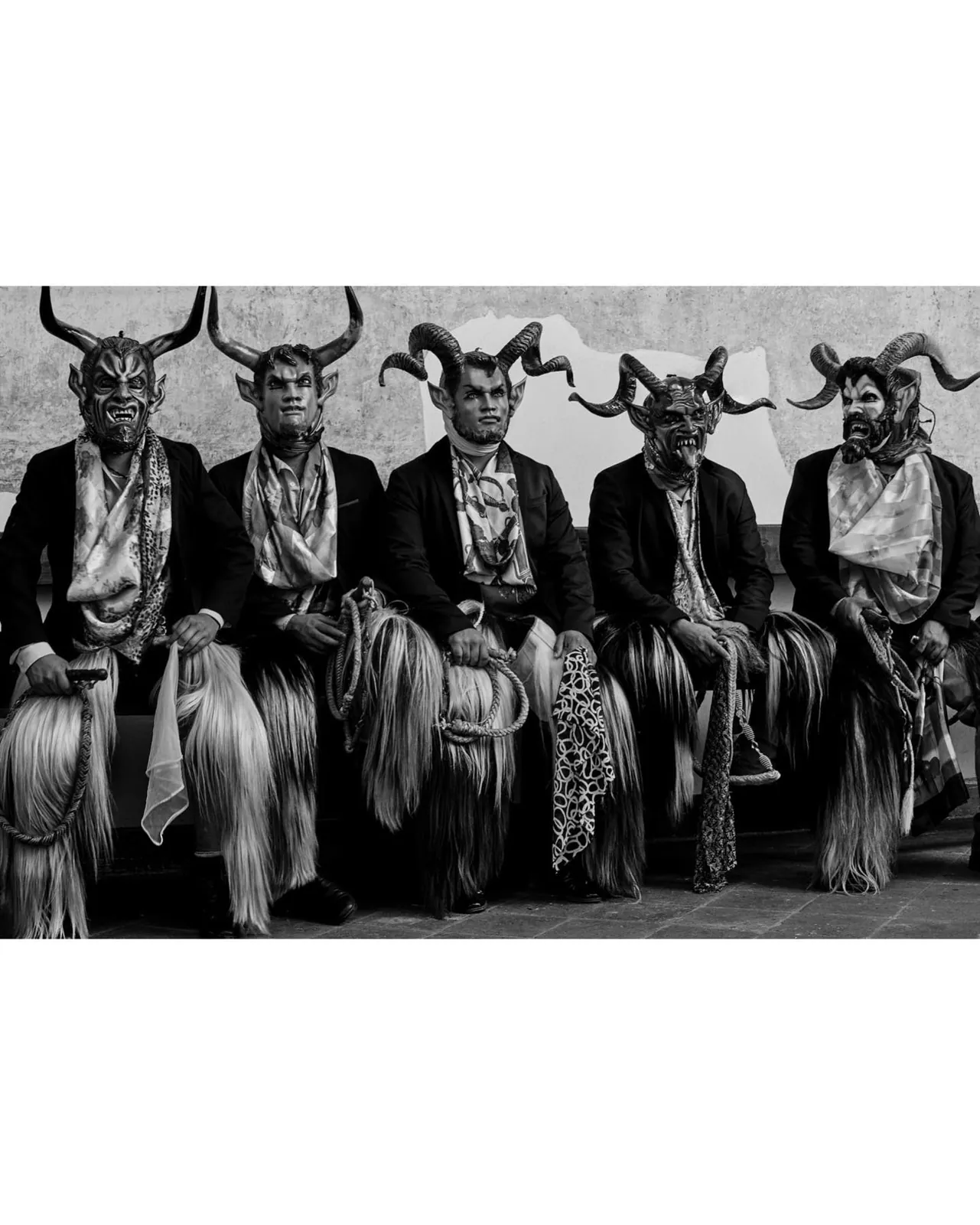 Five devil-masked figures in suits